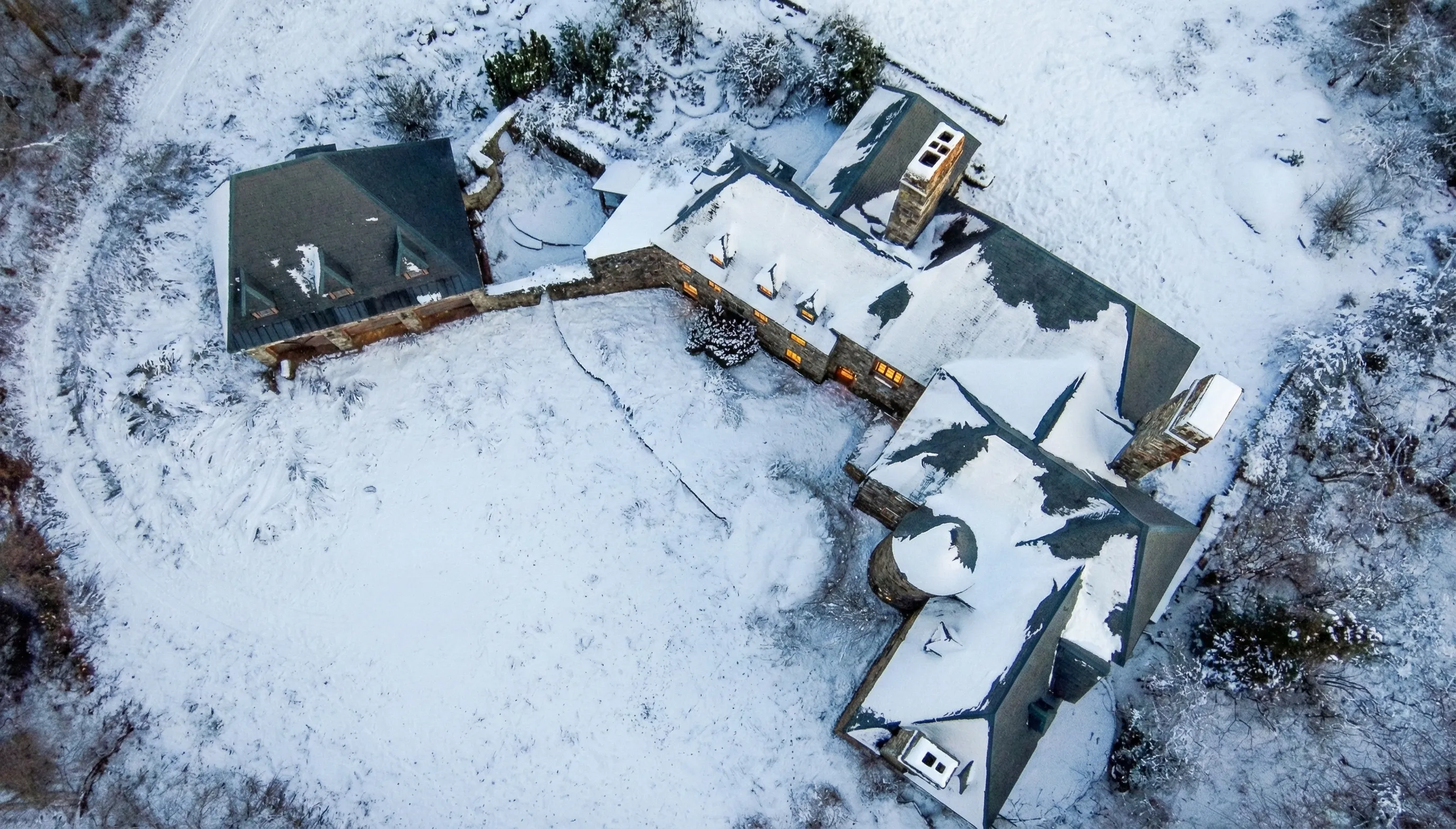 Aerial view of the castle estate in winter, windows glowing with warm light